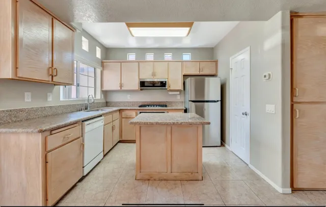 a kitchen with stainless steel appliances kitchen island granite countertop a stove a sink and a refrigerator