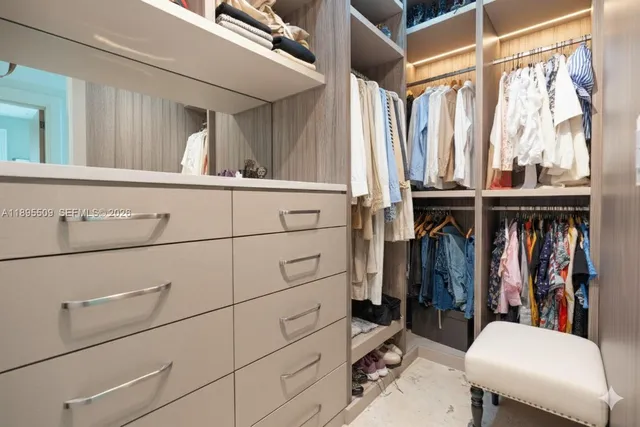 a view of walk in closet with clothes and shoes