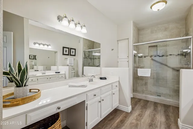 a bathroom with a double vanity sink a mirror a shower and a bathtub