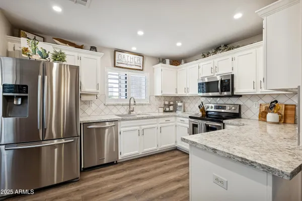 a kitchen with granite countertop stainless steel appliances a refrigerator sink microwave and cabinets