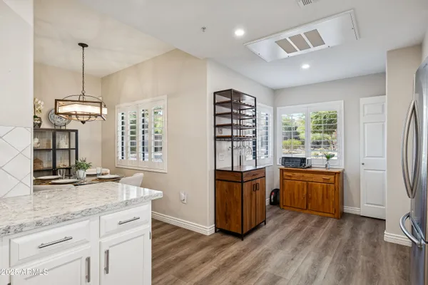 a kitchen with stainless steel appliances granite countertop a refrigerator a sink dishwasher a oven and a dining table with wooden floor