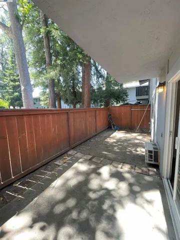 a view of backyard with wooden fence and large trees