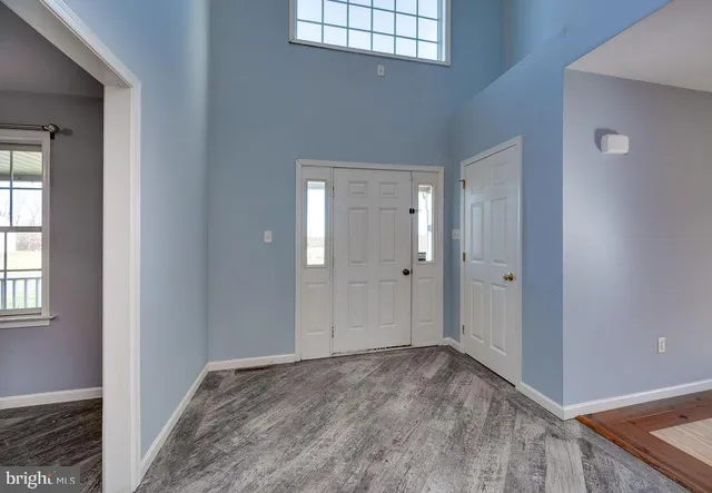 a view of an empty room with window and chandelier fan