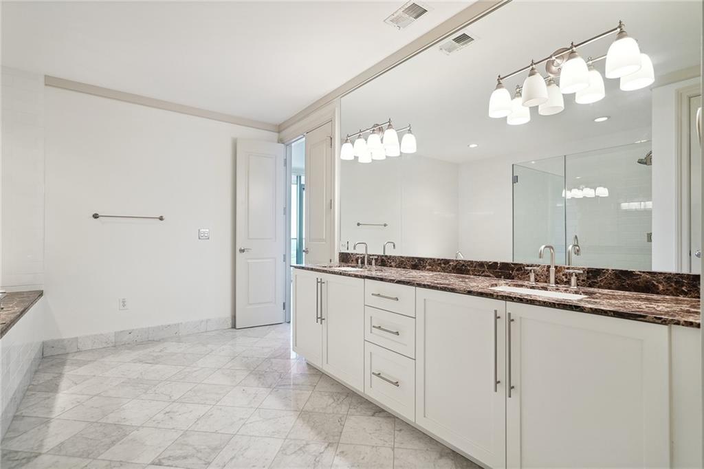3344 Peachtree Road Northeast, Unit 3202 Atlanta, GA 30326 - Photo 22 of 39 a bathroom with a granite countertop sink a large mirror and a shower