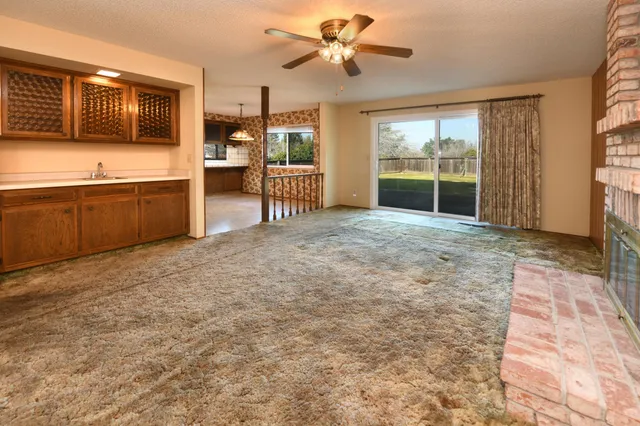 en empty room with windows and chandelier fan