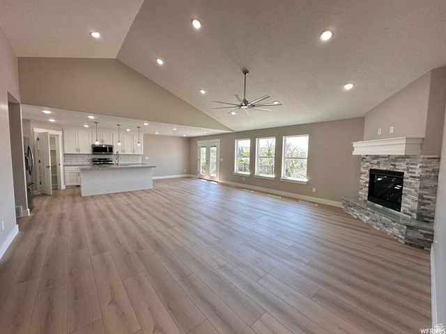 1171 West 2330 North Helper, UT 84526 - Photo 2 of 26 Unfurnished living room featuring lofted ceiling, a ceiling fan, recessed lighting, a fireplace, and light wood-style flooring