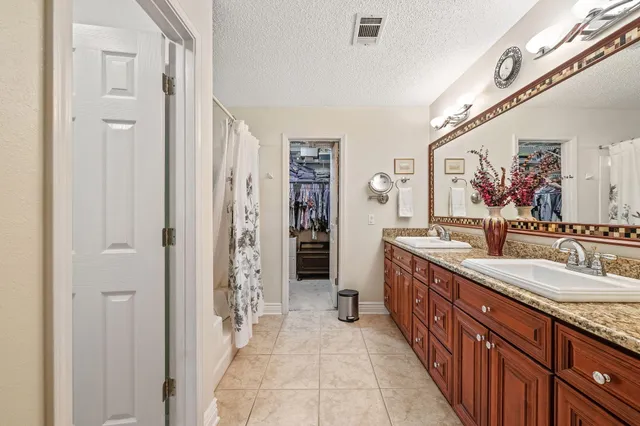 a spacious bathroom with a granite countertop double vanity sink a mirror and a shower