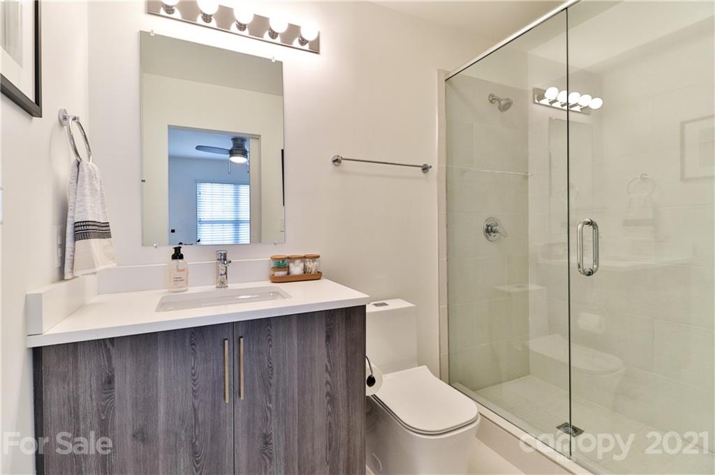 1537 Briar Creek Road, Unit A Charlotte, NC 28205 - Photo 19 of 30 a bathroom with a toilet a sink a mirror a shower and vanity