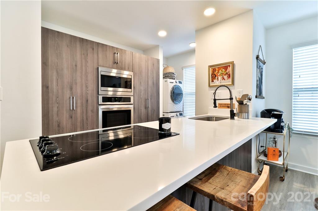 1537 Briar Creek Road, Unit A Charlotte, NC 28205 - Photo 7 of 30 a kitchen with stainless steel appliances kitchen island granite countertop a refrigerator and a stove top oven with wooden floor
