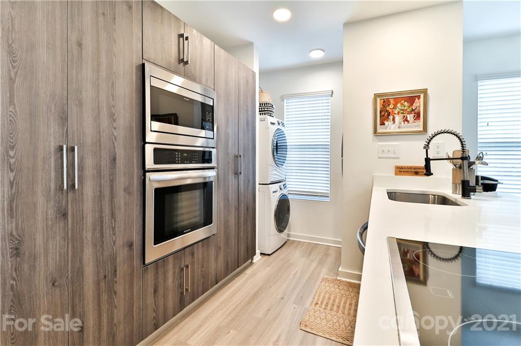 1537 Briar Creek Road, Unit A Charlotte, NC 28205 - Photo 8 of 30 a kitchen with stainless steel appliances a microwave a stove and white cabinets with wooden floor