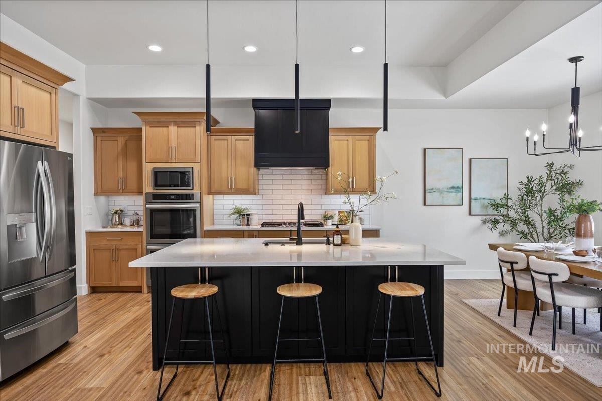 924 Trapper Peak Road Kimberly, ID 83341 - Photo 2 of 40 Kitchen with stainless steel appliances, a kitchen breakfast bar, an island with sink, and light wood finished floors
