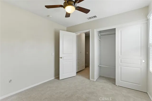 an empty room with closet and a chandelier fan