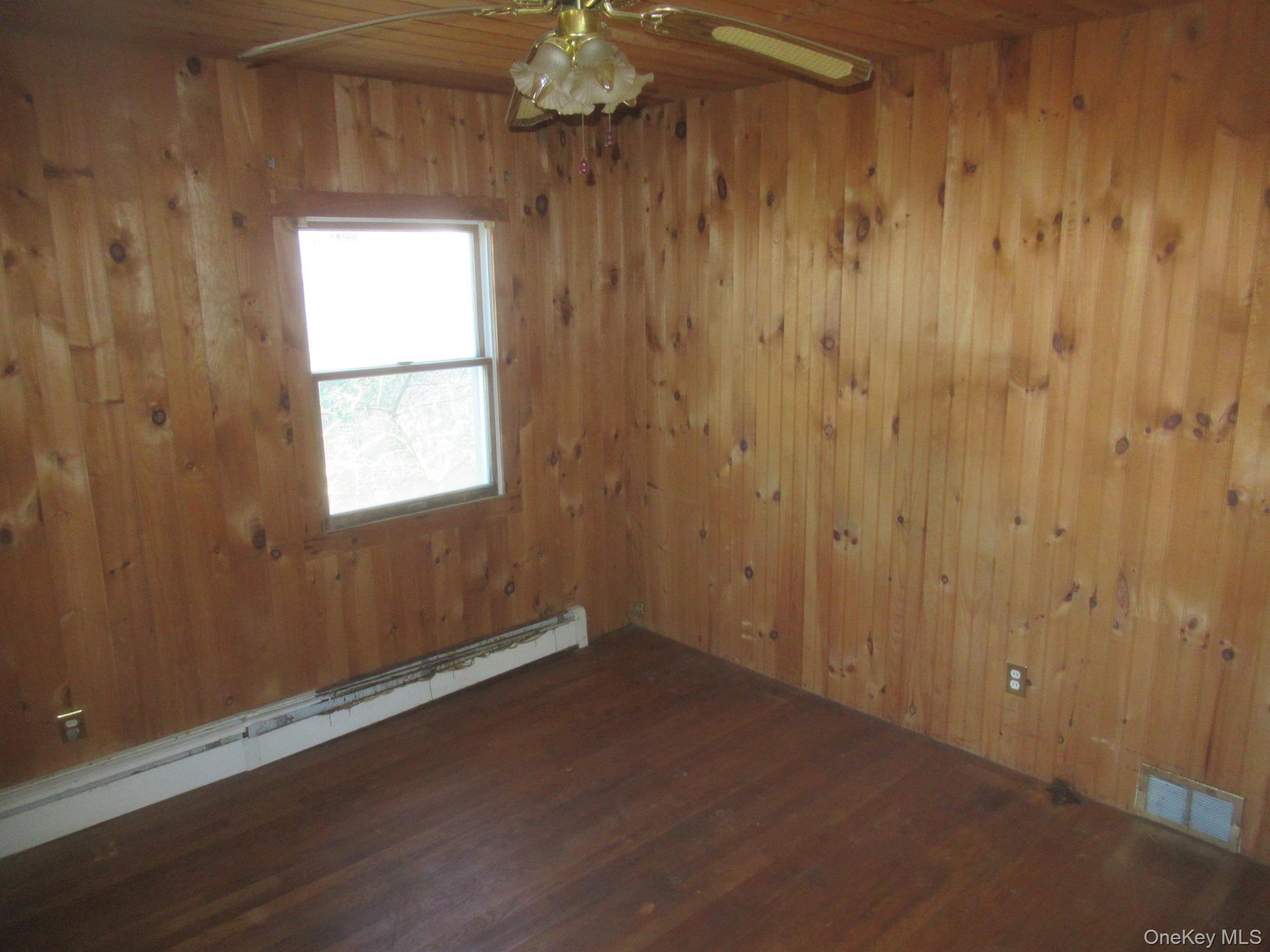 270 Bucks Hollow Road Mahopac, NY 10541 - Photo 8 of 10 Unfurnished room with baseboard heating, wood ceiling, wood walls, dark wood-style flooring, and ceiling fan