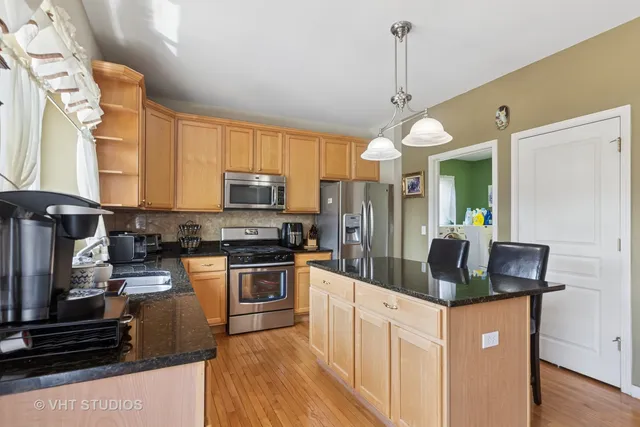 a kitchen with stainless steel appliances granite countertop a sink a stove and a refrigerator