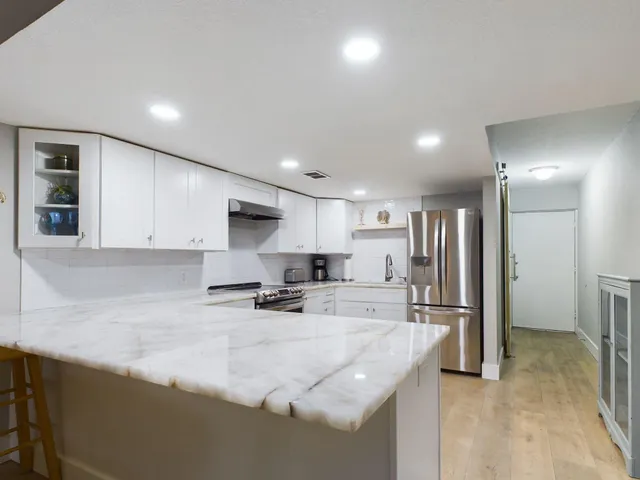 a kitchen with stainless steel appliances granite countertop a sink refrigerator and cabinets