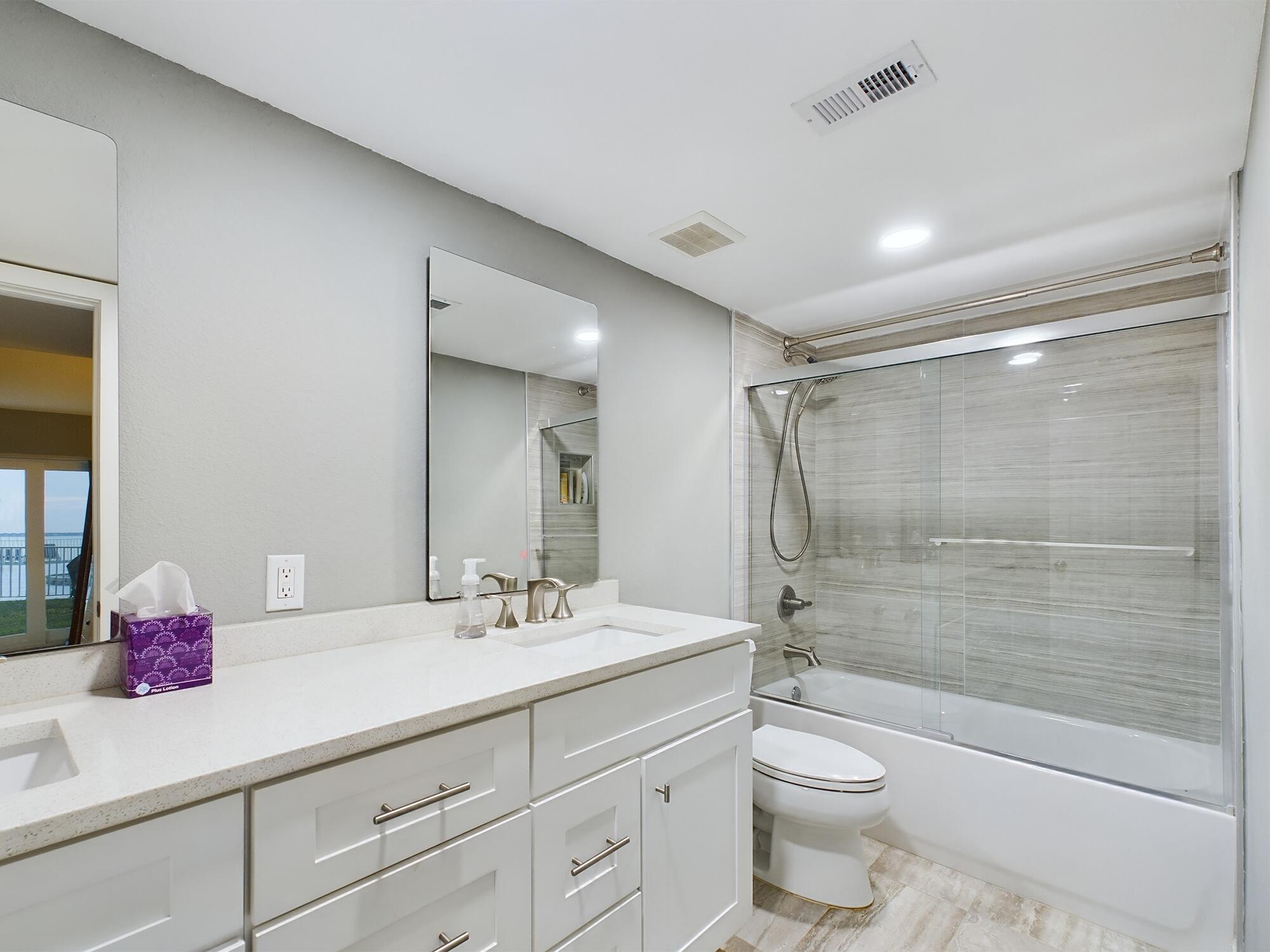 151 Calhoun Avenue, Unit 108 Destin, FL 32541 - Photo 14 of 30 a bathroom with a double vanity sink toilet mirror and shower