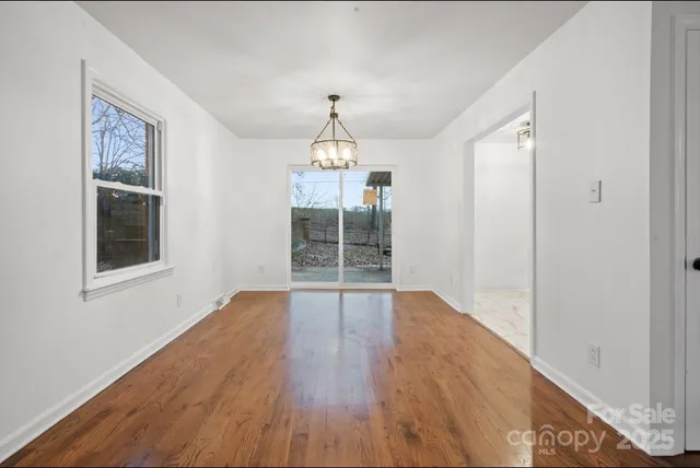 a hallway with wooden floor chandelier and entryway
