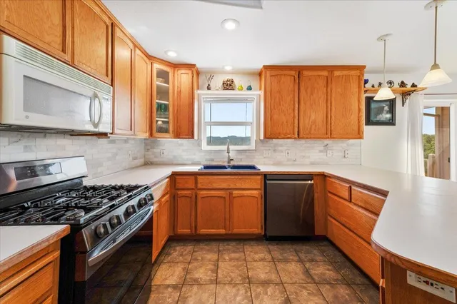 a kitchen with stainless steel appliances a stove a sink cabinets and a window