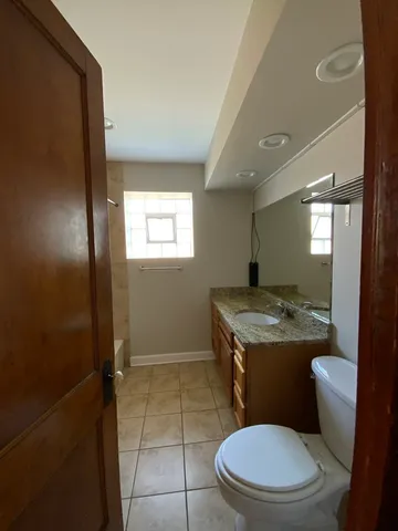 a bathroom with a granite countertop toilet sink and mirror