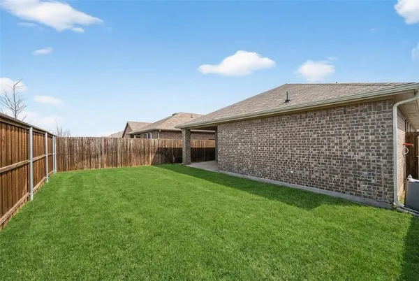 a view of a backyard with brick wall and wooden fence