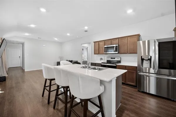a kitchen with stainless steel appliances granite countertop a sink a stove a refrigerator with a dining table and chairs