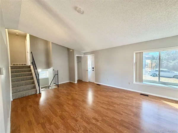 a view of an empty room with wooden floor and stairs