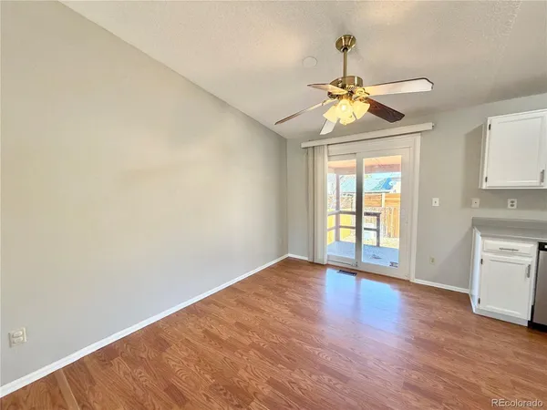 a view of an empty room with window and wooden floor