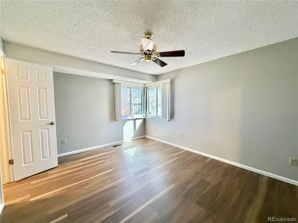 a view of empty room with wooden floor and fan
