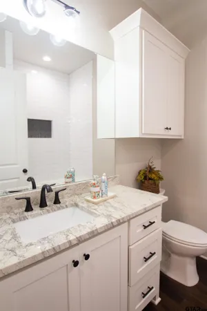 a bathroom with a granite countertop sink and a toilet