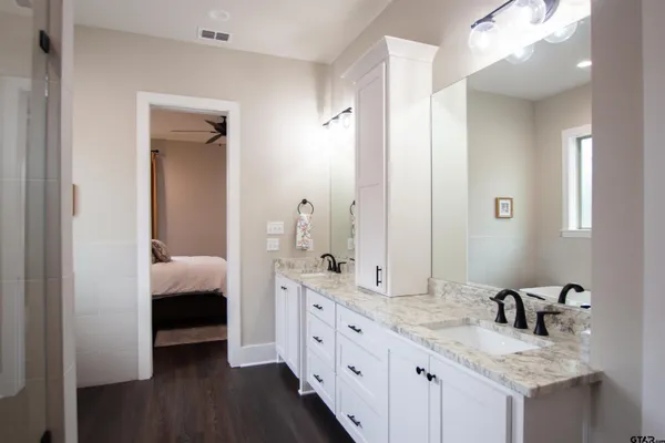 a en suite bathroom with a granite countertop double vanity sink and a mirror