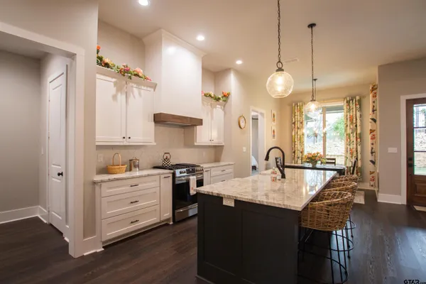 a large kitchen with granite countertop a stove a sink a window and chairs