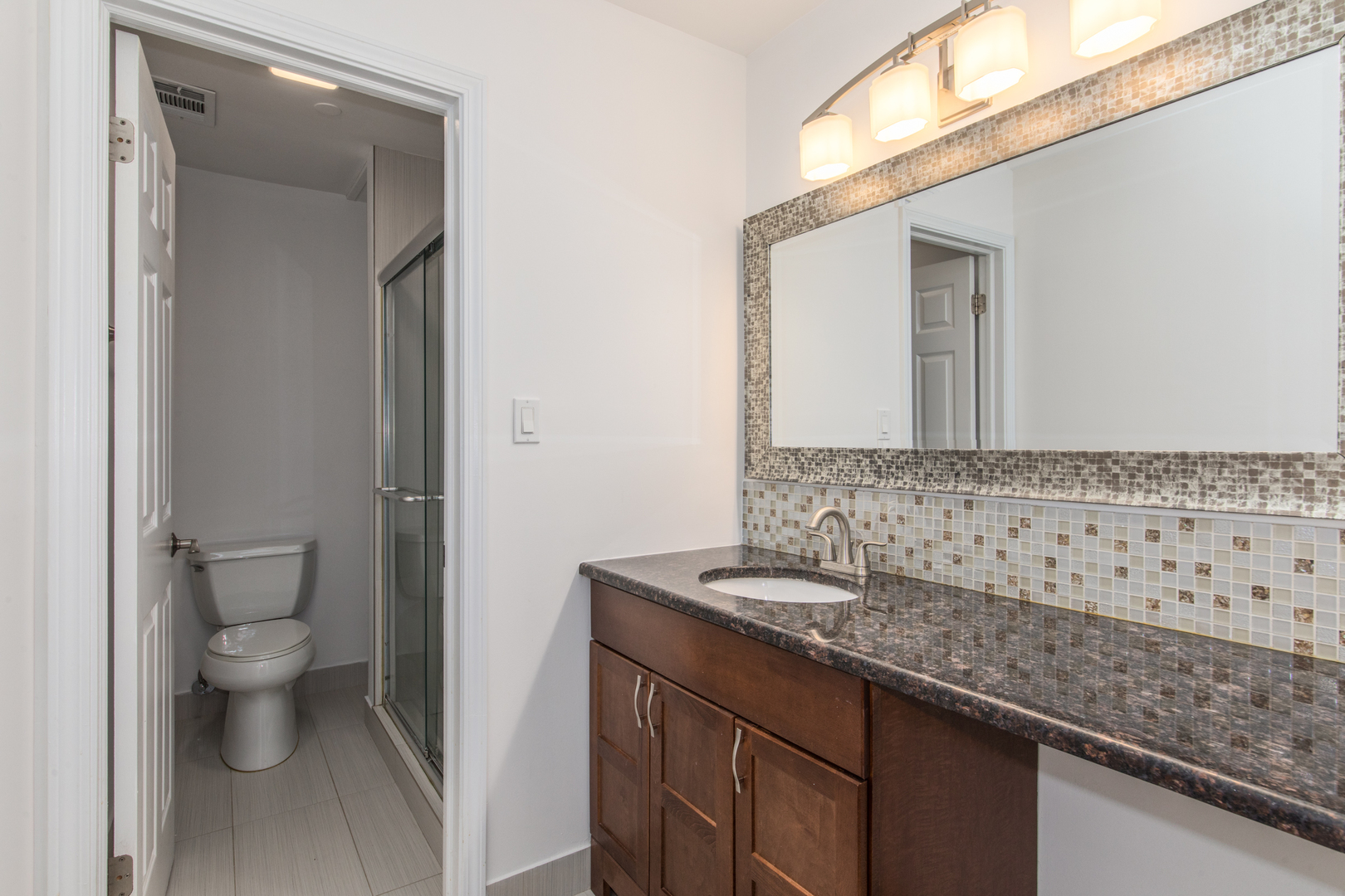 2021 Ammer Ridge Court, Unit 202 Glenview, IL 60025 - Photo 14 of 24 a bathroom with a granite countertop sink a toilet and a mirror