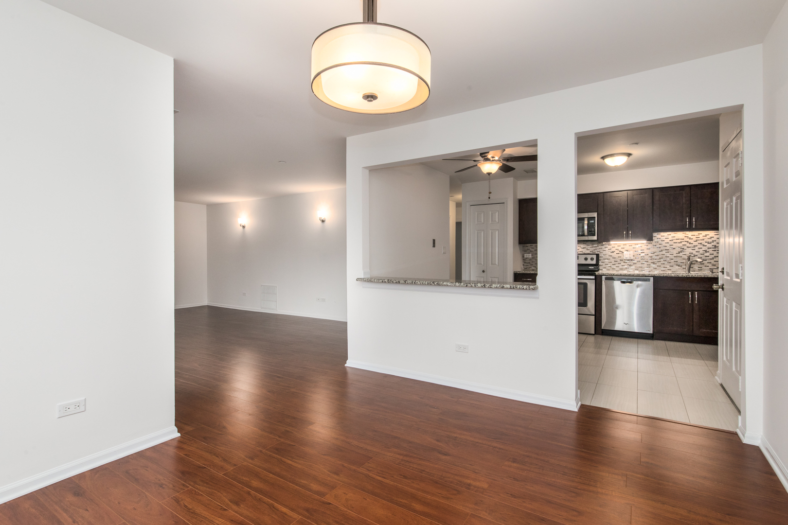 2021 Ammer Ridge Court, Unit 202 Glenview, IL 60025 - Photo 8 of 24 an empty room with wooden floor and kitchen view