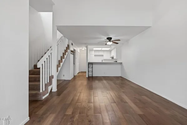 a view of a room with wooden floors and kitchen view