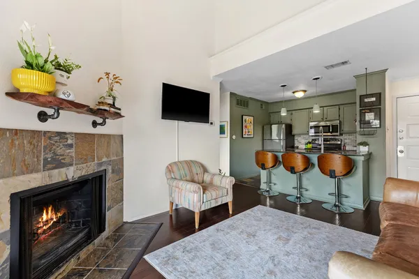 a living room with furniture a fireplace a flat screen tv and kitchen view