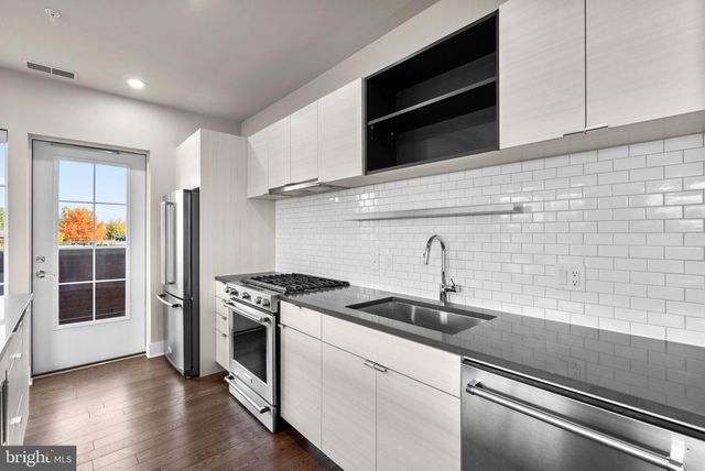 a kitchen with stainless steel appliances granite countertop a sink and a stove