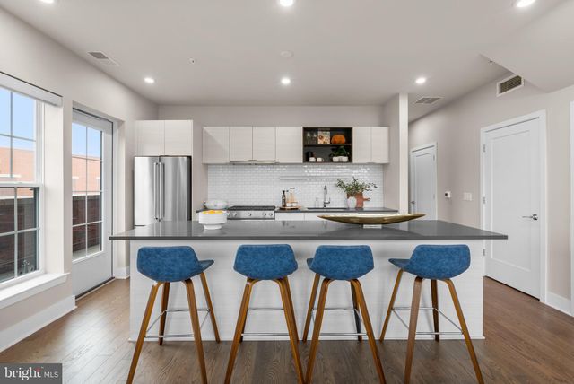 a kitchen with stainless steel appliances granite countertop a table chairs sink and cabinets