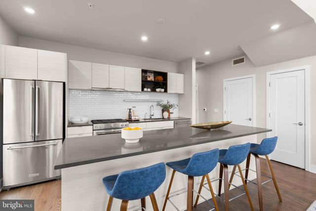 a kitchen with stainless steel appliances granite countertop a refrigerator a sink a stove a dining table and chairs