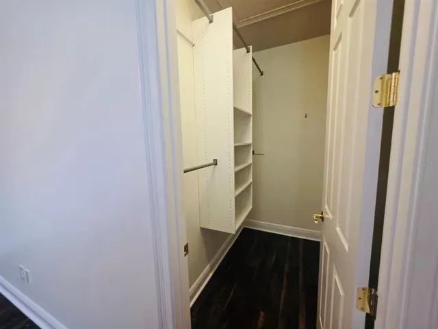 an empty room with wooden floor closet and windows