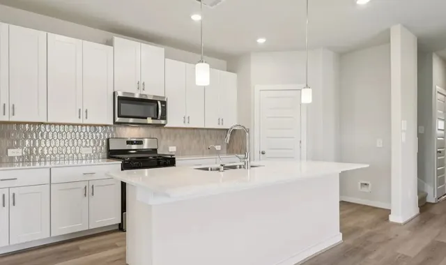 a kitchen with kitchen island a white cabinets and stainless steel appliances