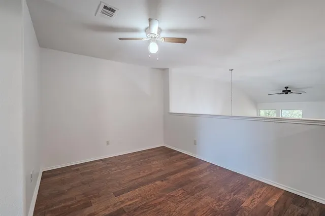 an empty room with a ceiling fan and wooden floor
