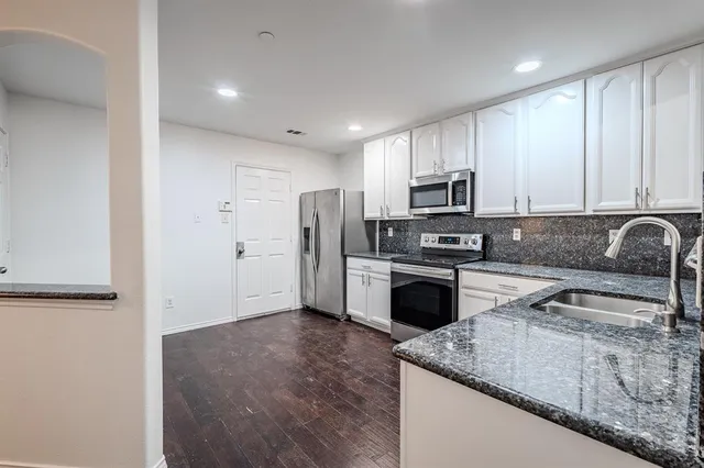 a kitchen with granite countertop a refrigerator sink and microwave