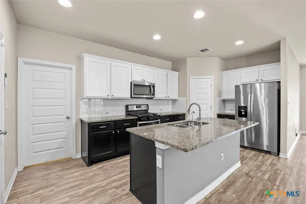 a kitchen with stainless steel appliances granite countertop a sink stove microwave and refrigerator