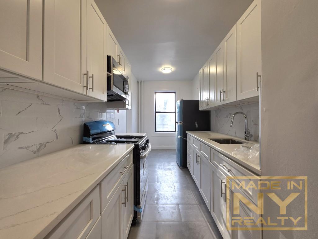 117-14 Union Turnpike, Unit EB2 Queens, NY 11415 - Photo 2 of 10 a kitchen with stainless steel appliances granite countertop a stove top oven a sink a counter space and cabinets