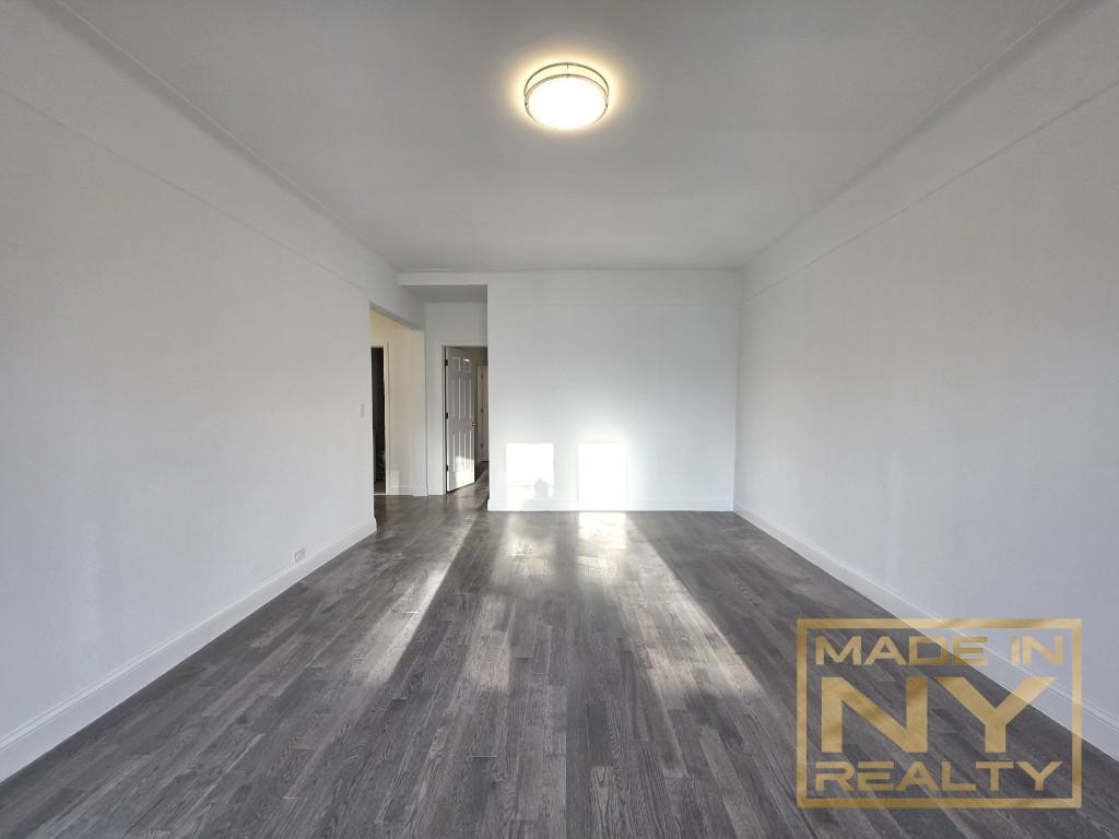 117-14 Union Turnpike, Unit EB2 Queens, NY 11415 - Photo 4 of 10 a view of an empty room with wooden floor and a window