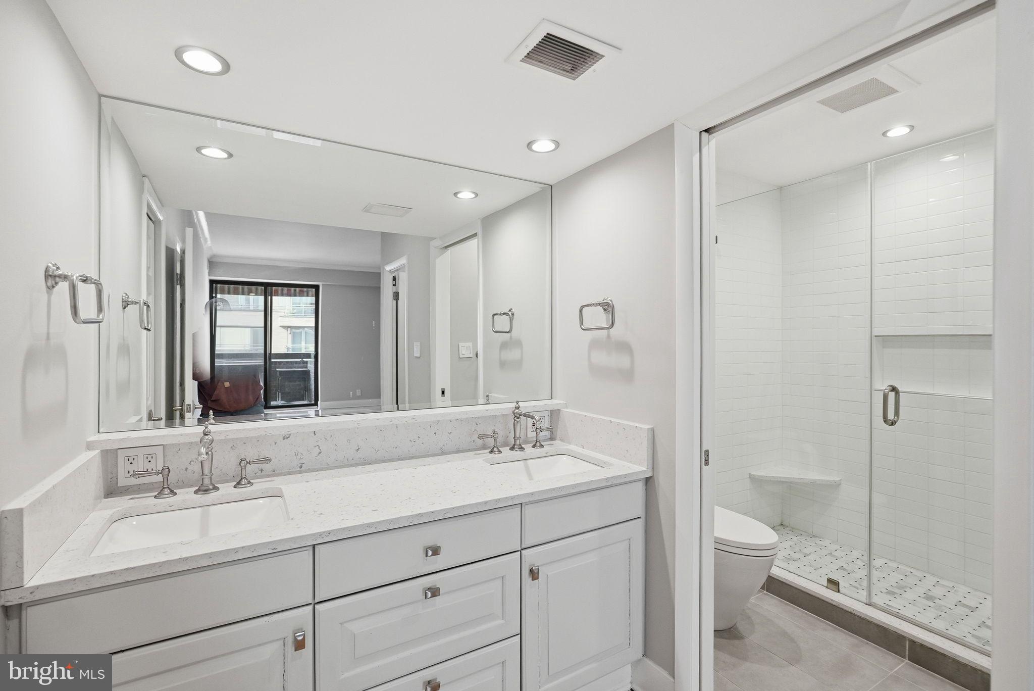 1140 23rd Street Northwest, Unit 1005 Washington, DC 20037 - Photo 10 of 22 a bathroom with a granite countertop double vanity sink a mirror and a toilet
