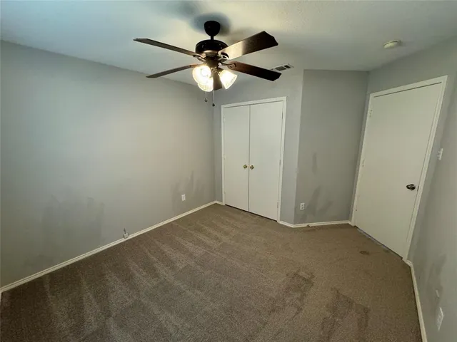 an empty room with a ceiling fan and a fan