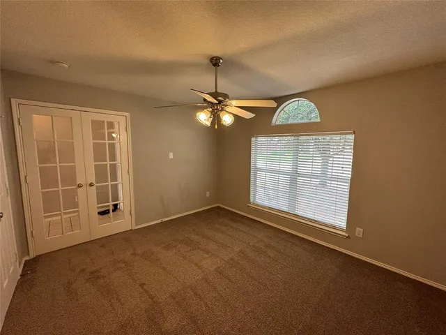 an empty room with chandelier fan and windows