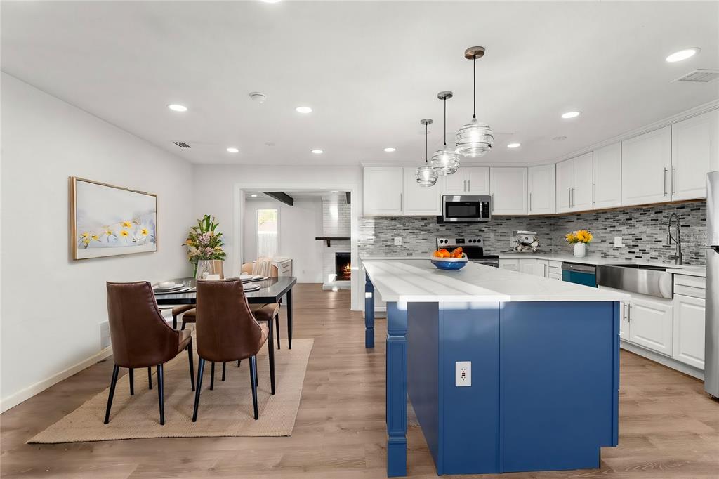 2203 Nottingham Road South Daytona, FL 32119 - Photo 2 of 40 a kitchen with stainless steel appliances granite countertop a stove top oven a sink a dining table and chairs with wooden floor