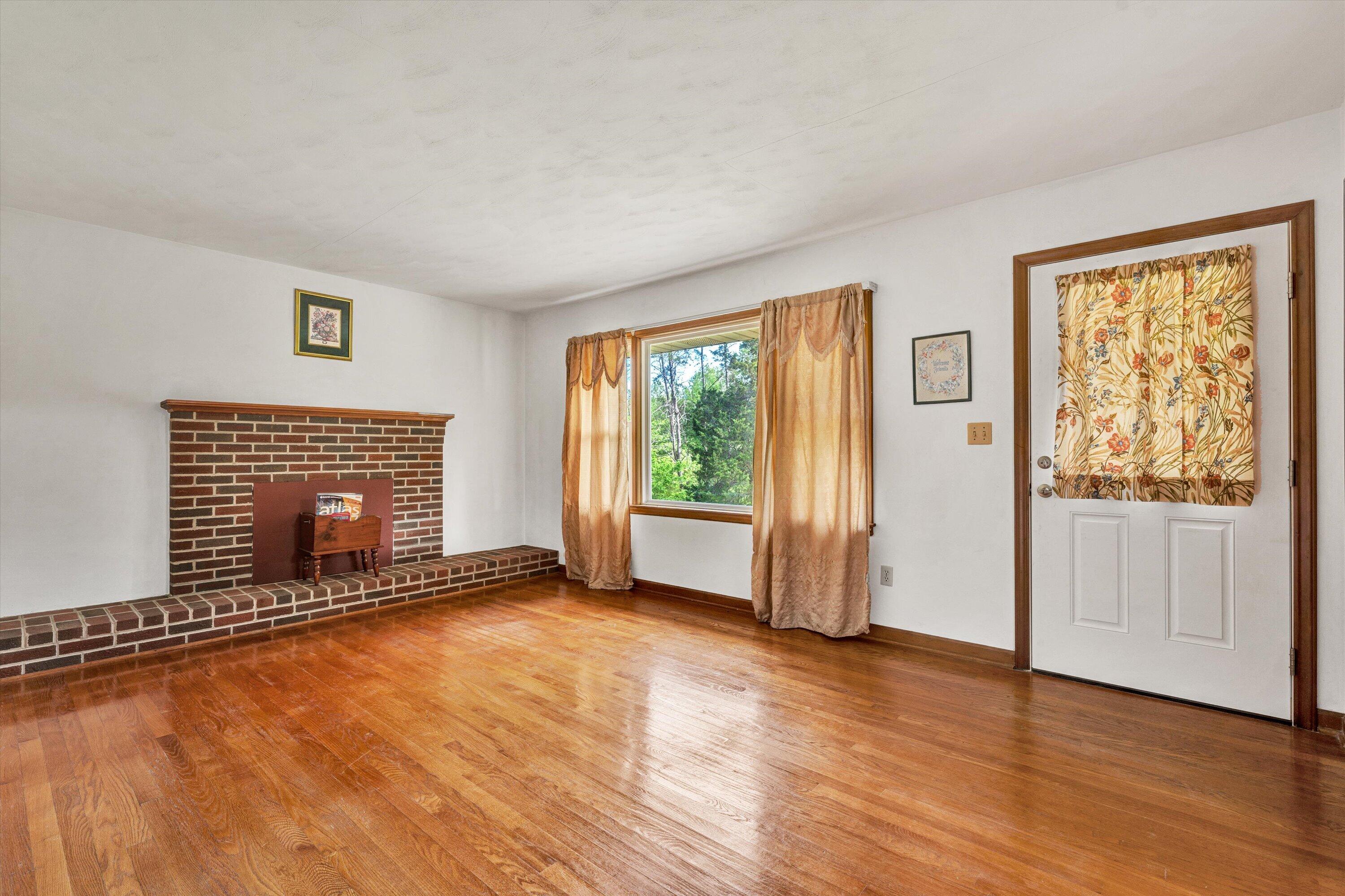 2296 Sandy Level Road Goodview, VA 24095 - Photo 11 of 48 a view of an empty room with glass door and wooden floor
